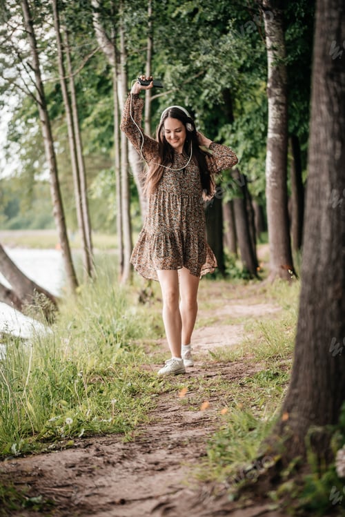 Preview: girl in the park with headphones running and dancing, active lifestyle, listening to music, cheerful
