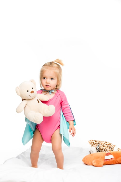 Preview: toddler girl in superhero cape holding teddy bear isolated on white