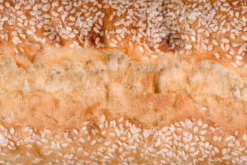 Preview: Crispy wheat flour baguette with sesame seeds on a wooden cutting board