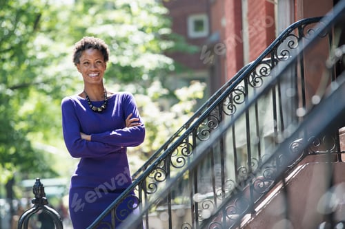 Preview: A woman wearing a purple dress, standing on the steps outside a townhouse.