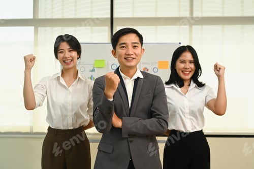Preview: Happy business team raising fists making yes gesture celebrating victory.
