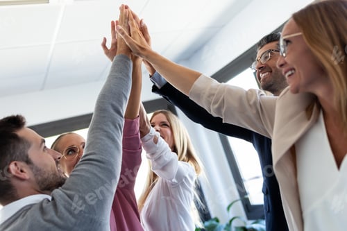 Preview: Group of successful young businesspeople holding up their right hands on coworking place.