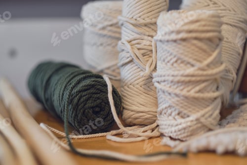 Preview: Balls of white yarn and rustic sticks on table. Good for macrame and handicrafts banners.