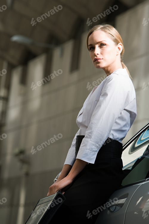 Preview: Businesswoman leaning on a car