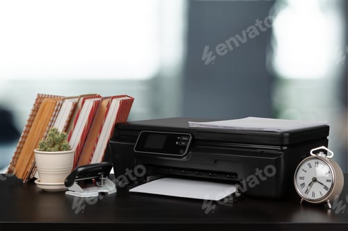 Preview: Stack of books and home printer against blurred background