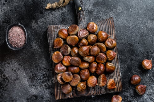 Preview: Raw chestnuts on a wooden cutting board. Black background. Top view