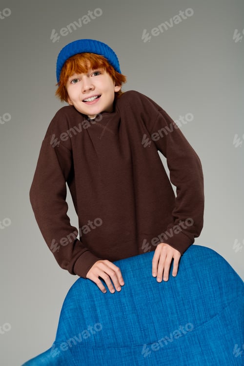 Preview: Creative redhead boy poses in casual outfit, showcasing child fashion in studio