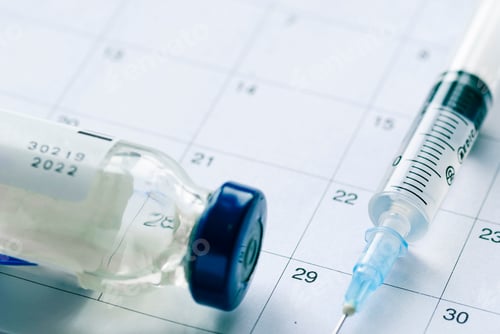 Preview: Vaccine vial with syringe needle on calendar