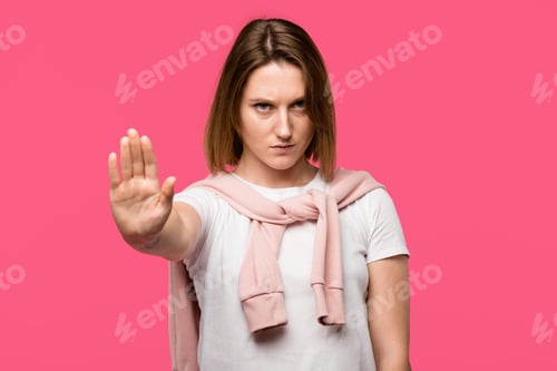 Preview: serious young woman showing stop gesture isolated on pink