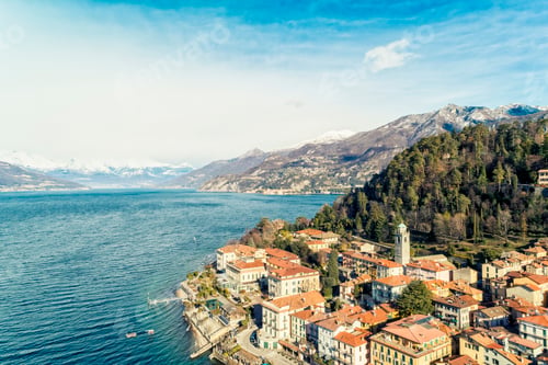 Preview: Aerial view of Bellagio village on Como lake with blue sky and the Alps in the background