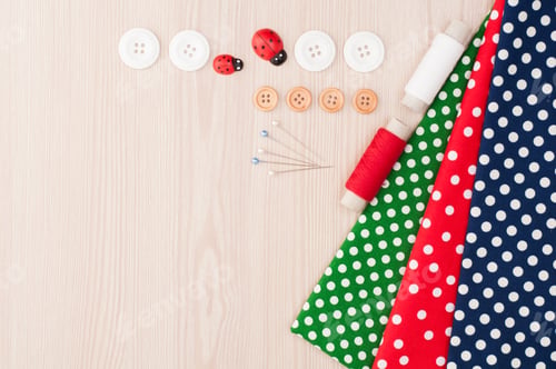 Preview: Polka dot fabric for sewing and accessories for needlework on wooden background. Spool of thread