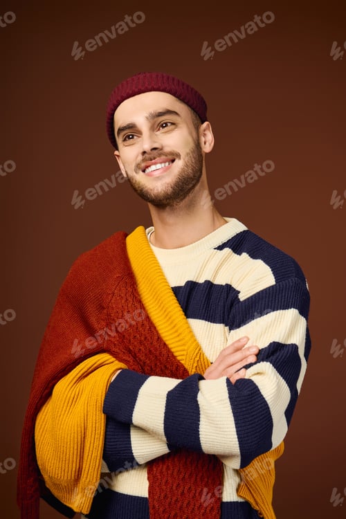 Preview: Handsome young man embraces winter fashion trends in stylish beanie and knitted sweater