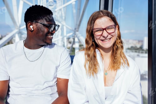 Preview: Smiling young couple enjoying a ride on a Ferris wheel, showcasing joy and connection