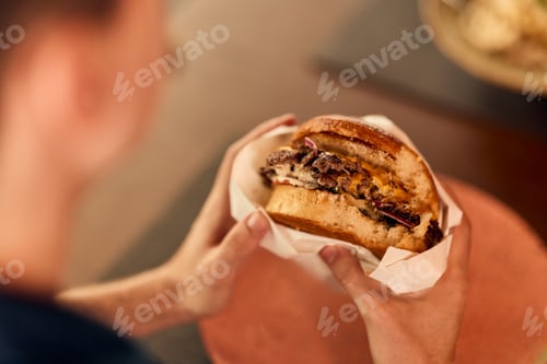 Preview: Man Holding Freshly Prepared Burger With Juicy Patty In A Restaurant Setting