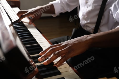 Preview: African-American man playing piano indoors, closeup. Talented musician