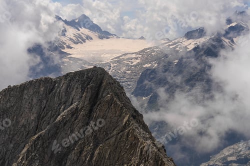 Preview: Jagged Mountain Ridge with Snow-Capped Peaks and Misty Clouds