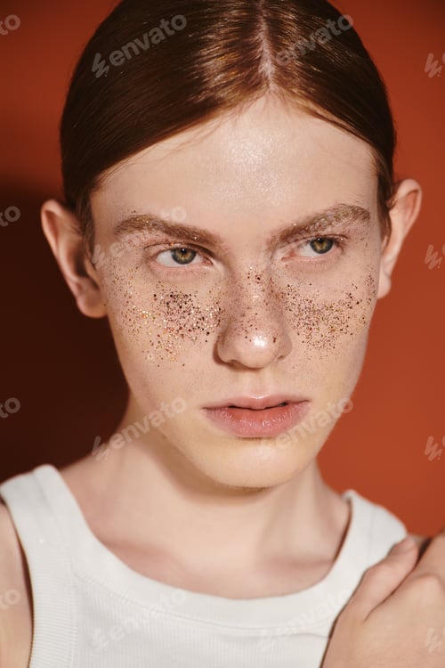 Preview: Stylish young queer man showcasing modern fashion with a unique look in a vibrant setting