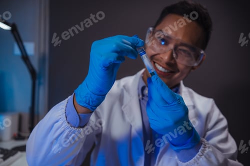 Preview: Scientist wearing lab coat and gloves holding a test tube with blue liquid, smiling, in laboratory