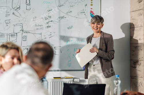 Preview: Smiling businesswoman presenting new project to her colleagues in the office