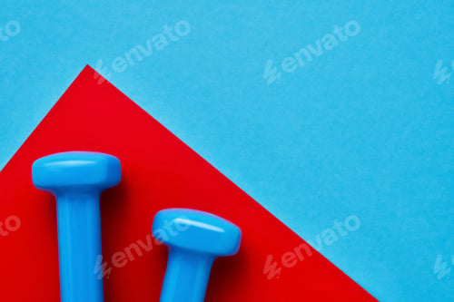 Preview: Blue dumbbells lie on red-blue background. The concept of healthy lifestyle. Copy space, top view