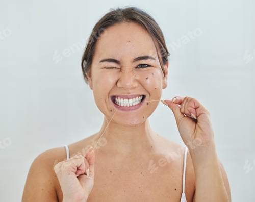 Preview: Keeping up with my dental hygiene. Shot of a young woman flossing her teeth in a bathrroom at home.
