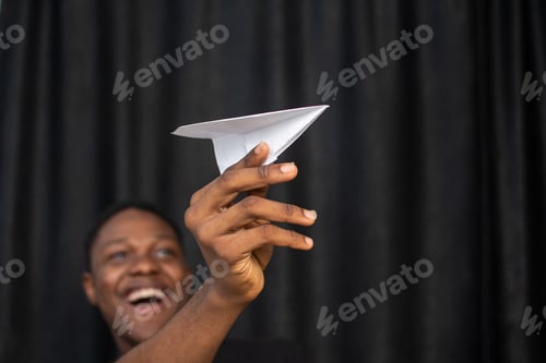 Preview: Young African male holding a white paper plane