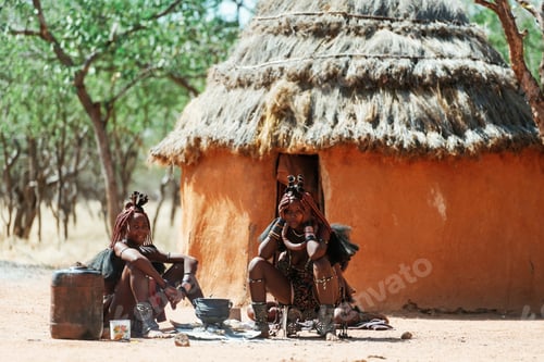 Preview: Namibia, Africa - June 14, 2021: Ethnic people, women are together near old styled home