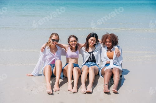 Preview: Happy childrens sitting on sand at beach. Teens playing and enjoying with friends at the sea.