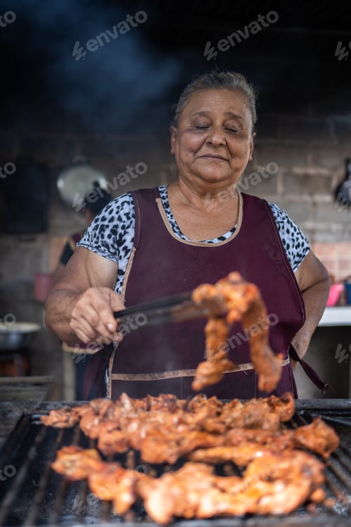 Preview: Vertical photo of a latin woman cooking meat on a grill