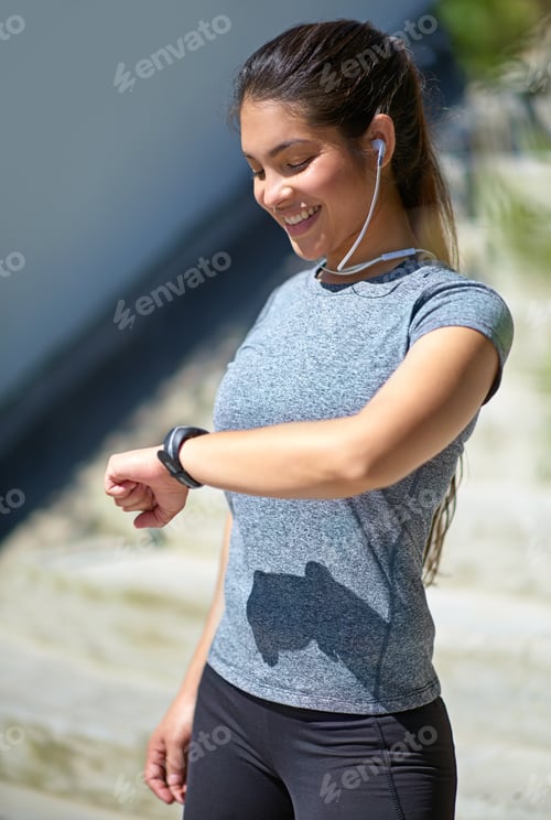 Preview: Making great progress. Shot of a young woman checking her watch while out exercising.
