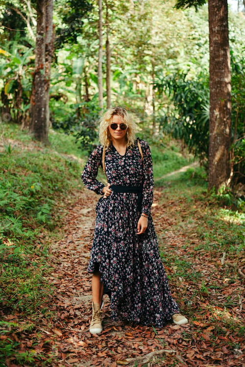 Preview: attractive woman in dress and sunglasses posing on path in jungle
