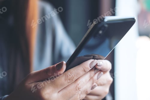 Preview: Closeup image of hands holding and using smart phone in modern cafe