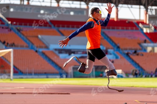 Preview: Asian para-athletes with prosthetic blades sprint on a running track at stadium.