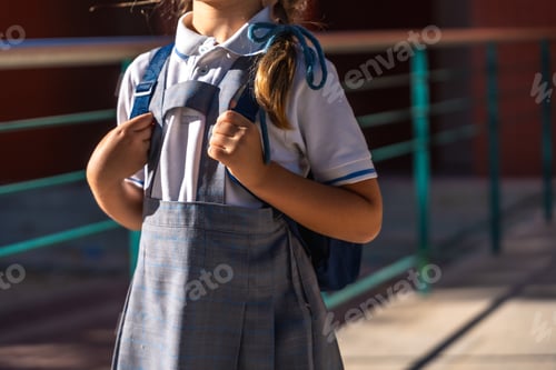 Preview: Little girl wearing school uniform holding backpack