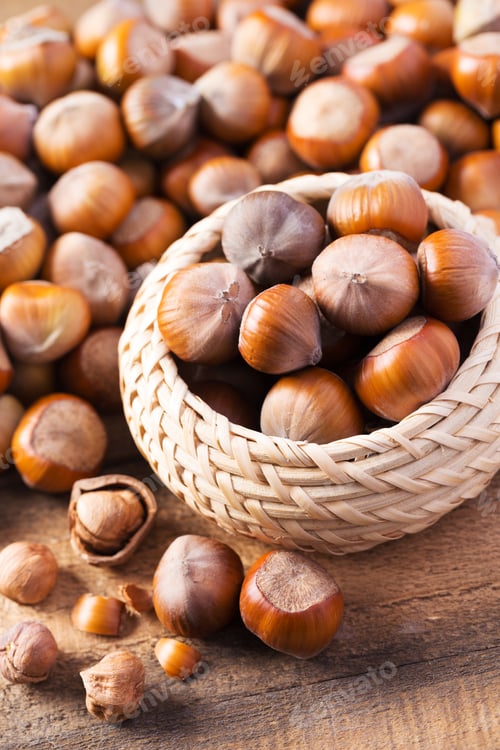 Preview: Freshly harvested hazelnuts in a wicker basket on a rustic wooden table