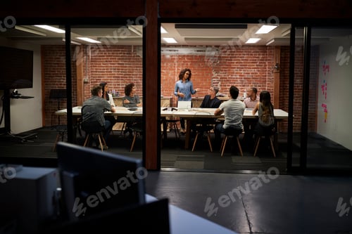 Preview: Business Team Having Late Night Meeting Sitting Around Boardroom Table