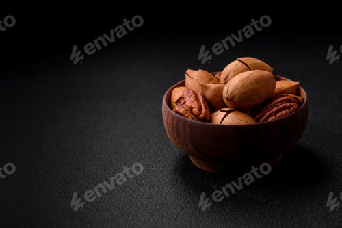 Preview: Pecan nuts in shell and peeled in a wooden round bowl