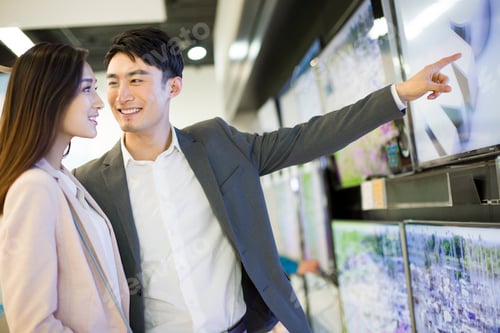 Preview: Young couple buying television in electronics store