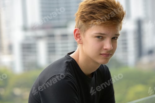 Preview: Young handsome teenage boy against view of the city outdoors