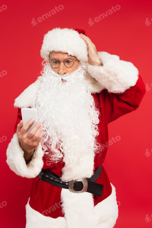 Preview: Worried santa claus using smartphone isolated on red