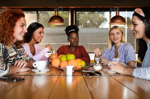 Preview: Group of young female friends having fun in cafe, talking and laughing while sitting at table.