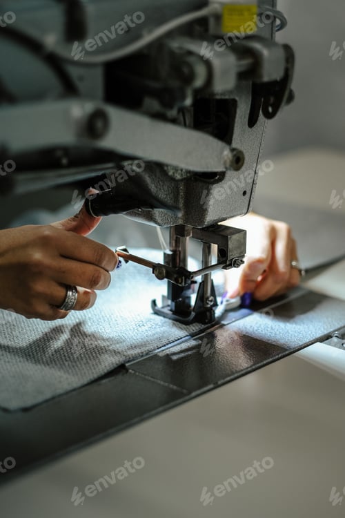 Preview: Vertical closeup shot of a female operating an industrial sewing machine