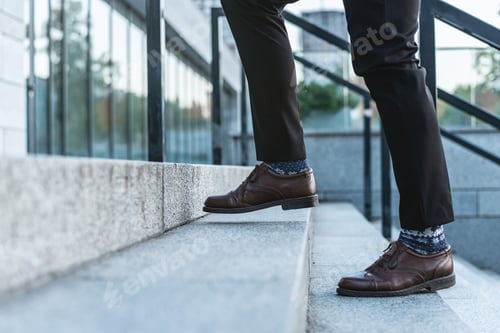 Preview: Сlose-up of male legs in business trousers and shoes walking up the stairs