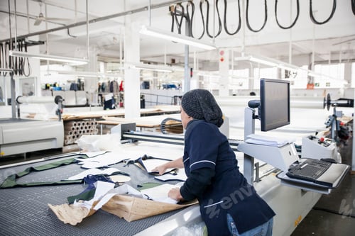 Preview: Factory worker removing cut textile pattern from pattern cutting machine in clothing factory