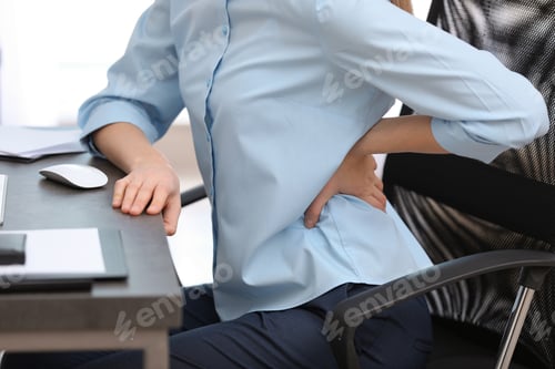 Preview: Young woman suffering from back pain in office, closeup