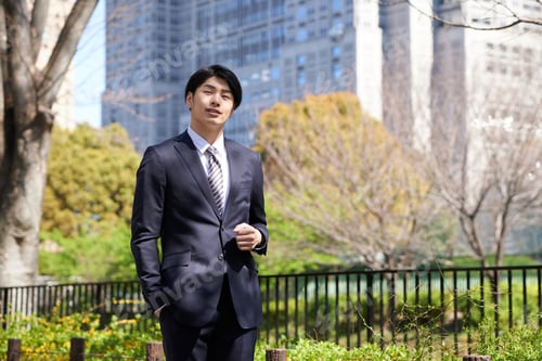 Preview: A Japanese male businessman standing in the background of a building.