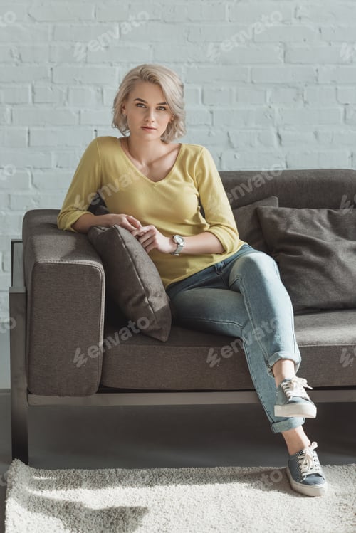 Preview: beautiful girl sitting on sofa and looking at camera