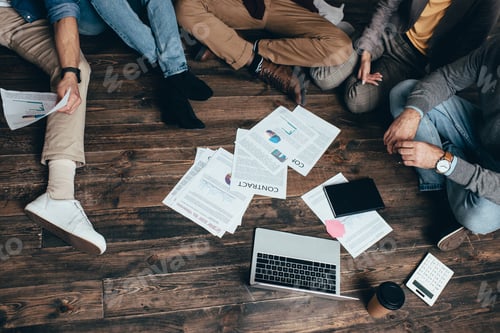 Preview: cropped view of multiethnic group of colleagues sitting on floor and working together on new project