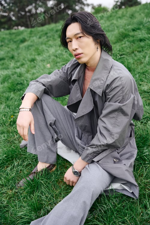 Preview: Stylish young man enjoys the vibrant greenery of a park in a trendy grey outfit