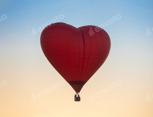 Preview: Hot Air Balloon in Red Heart Shape at sunset sky background